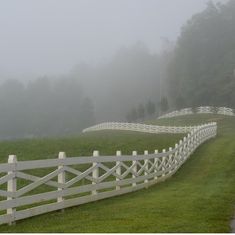 a white fence in front of a grassy field