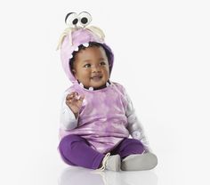 a baby sitting on the floor wearing a purple costume