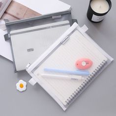 a notepad, pen and paper on a desk with a cup of coffee next to it