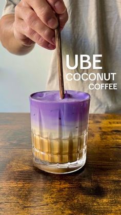 a person is stirring some liquid into a cup with the words ube coconut coffee on it