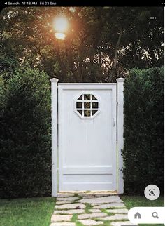 an open white door sitting in the middle of a lush green yard with stepping stones