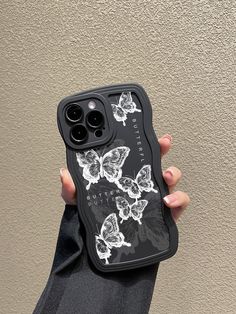 a woman holding up her phone case with butterflies on the front and back cover in black