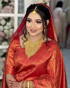 a woman in an orange and gold bridal outfit with jewelry on her head, smiling at the camera