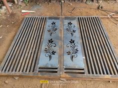 two metal grates with designs on them sitting in the dirt next to construction equipment