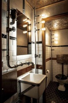 a bathroom with a sink, toilet and pipes on the wall next to each other