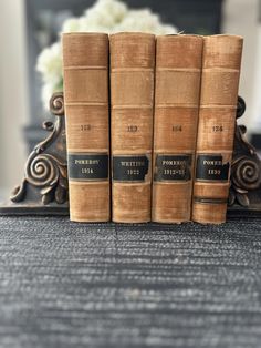 three books sitting on top of a table next to a vase with flowers in it