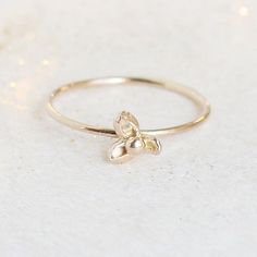 a gold ring with a tiny flower on the front and side, sitting on a white surface