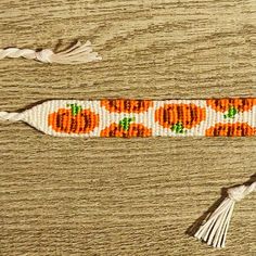 an orange and white beaded bracelet with tassels on top of a wooden table