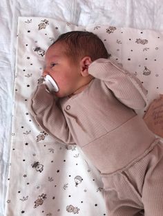 a baby is laying down with a pacifier in its mouth and writing on the pillow