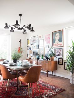 a dining room table with chairs and pictures on the wall above it, along with potted plants