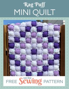 a purple and white quilt sitting on top of a wooden fence next to a box