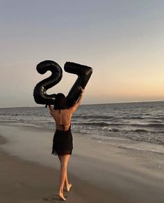 a woman standing on top of a beach holding an inflatable number