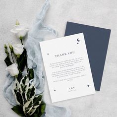 a thank you card and some flowers on a white surface with blue paper next to it