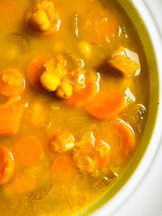 a bowl of soup with carrots, corn and meat in it's broth