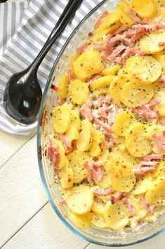 a bowl filled with potatoes and meat on top of a table next to a spoon