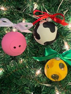 three ornaments hanging from a christmas tree with ribbons on them, one pig and the other cow