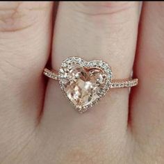 a woman's hand with a heart shaped diamond ring on her finger and an engagement band