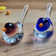 two glass birds sitting on top of a wooden table