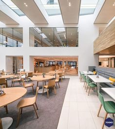 the interior of a restaurant with tables and chairs, windows, and skylights on the ceiling