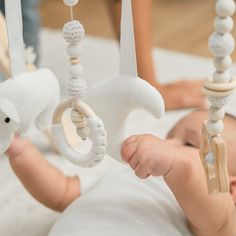 a baby is laying down in a crib with toys hanging from it's sides