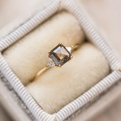 an engagement ring in a white box with gold trimmings and two diamonds on the band