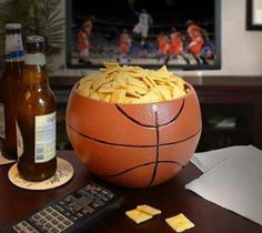 a basketball sitting on top of a table next to two beer bottles and a remote control