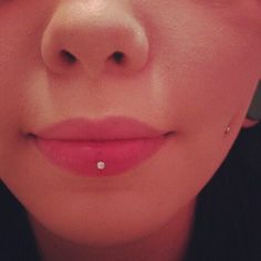 a close up view of a woman's nose with a diamond ring on it