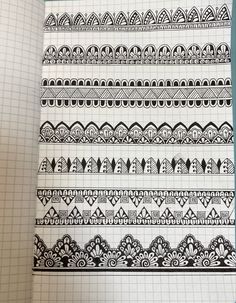 some black and white designs on a sheet of paper in a notebook with pencils