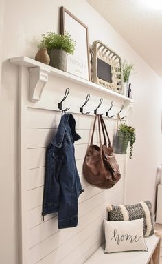 a coat rack with two coats hanging on it next to a bench and purses