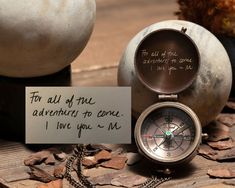 an old compass with a note attached to it sitting on the ground next to other items