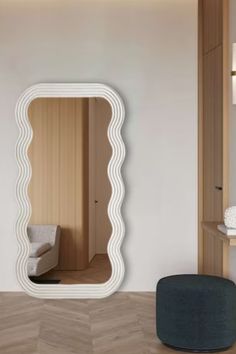 a mirror sitting on top of a wooden floor next to a white chair and ottoman