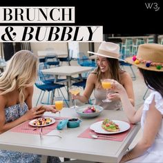 three women sitting at a table with food and drinks