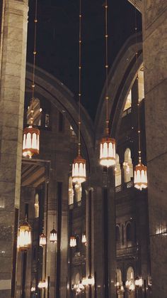 chandeliers hanging from the ceiling in an ornate building with columns and arches at night