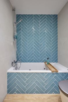 a bath tub sitting next to a toilet under a shower faucet in a bathroom