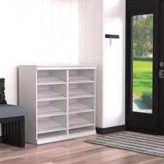 a white bookcase sitting next to a black door in a room with wooden floors