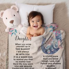 a baby laying in bed next to a teddy bear and blanket with the words daughter written on it