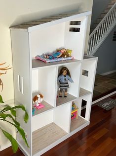 a doll house with dolls in it on the floor next to a plant and stairs