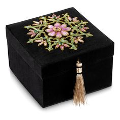 a black velvet box with a tasseled handle and floral design on the lid