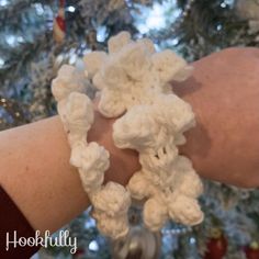 white crocheted bracelets are displayed on a woman's arm in front of a christmas tree