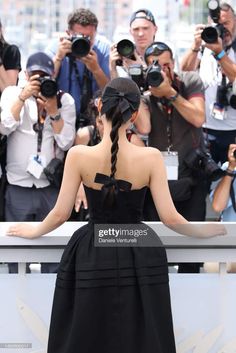 the back view of a woman in a black dress with her hands on her hips