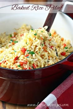 a bowl filled with rice and vegetables on top of a wooden table next to a red napkin