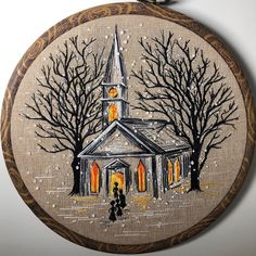 a cross stitched picture of a church surrounded by trees and people walking in the snow