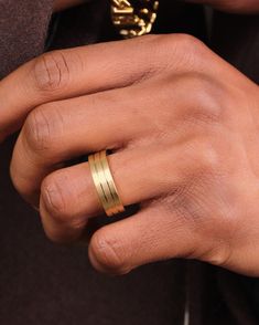 a close up of a person's hand with a gold ring on their finger