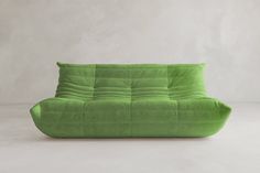 a green couch sitting on top of a white floor