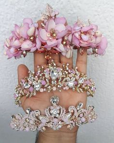 a hand holding several pink flowers and tiaras