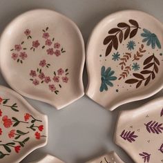 four ceramic dishes with designs on them arranged in the shape of flowers and leaves,