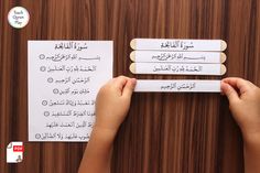 two hands are holding some paper with arabic writing on it and another hand is pointing at them