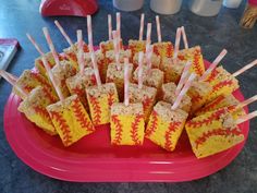 rice krispy treats are arranged on sticks in a red tray with baseballs painted on them