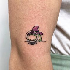 a small tattoo on the arm of a person wearing a hat and holding a camera