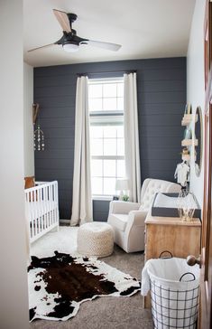 a baby's room with gray walls, white furniture and a cow rug on the floor